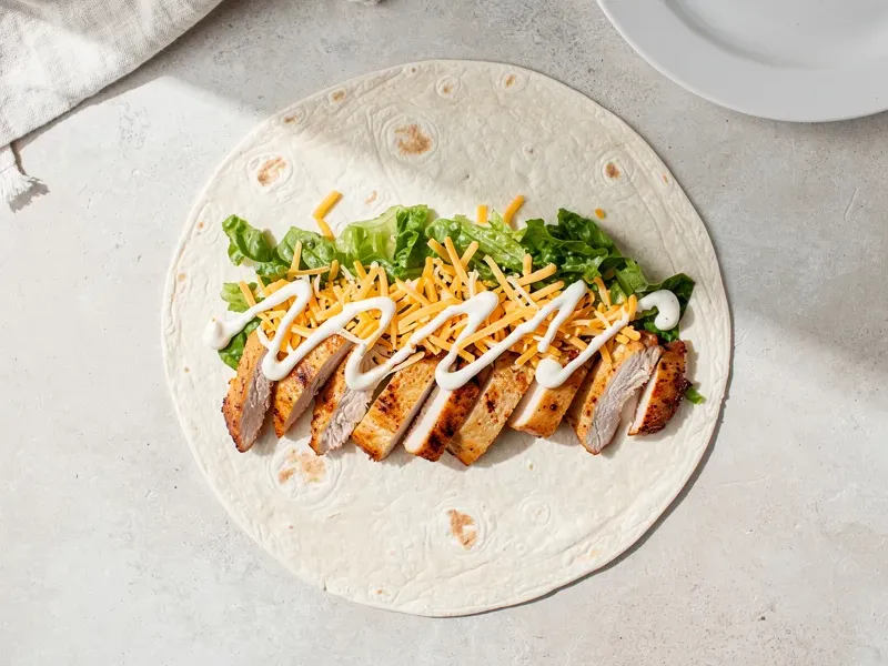 Step 4: Lay the warmed tortilla flat on a clean surface. Place the chicken strips in a l