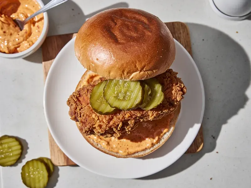 Step 6: Assemble the sandwich: spread the spicy Cajun mayo on the bottom bun, add the fr