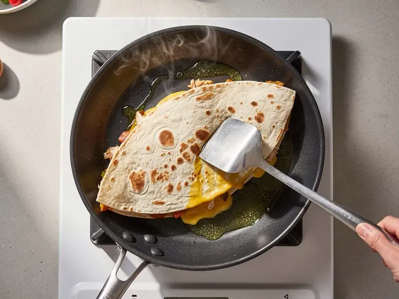 Step 5: Fold the tortilla in half to cover the fillings. Press gently with a spatula. Co